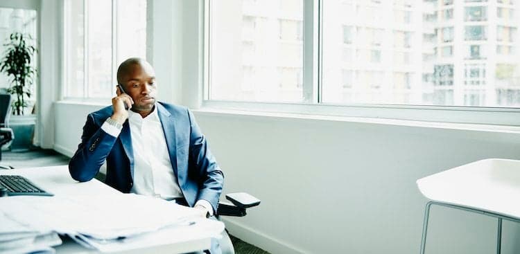 person sitting at a desk talking on the phone looking stressed