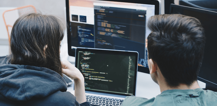 two people looking at code on computer screens