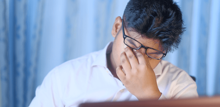 person rubbing their eyes at work