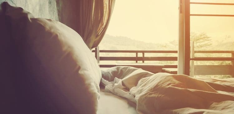 a bed next to a window in bright sunlight