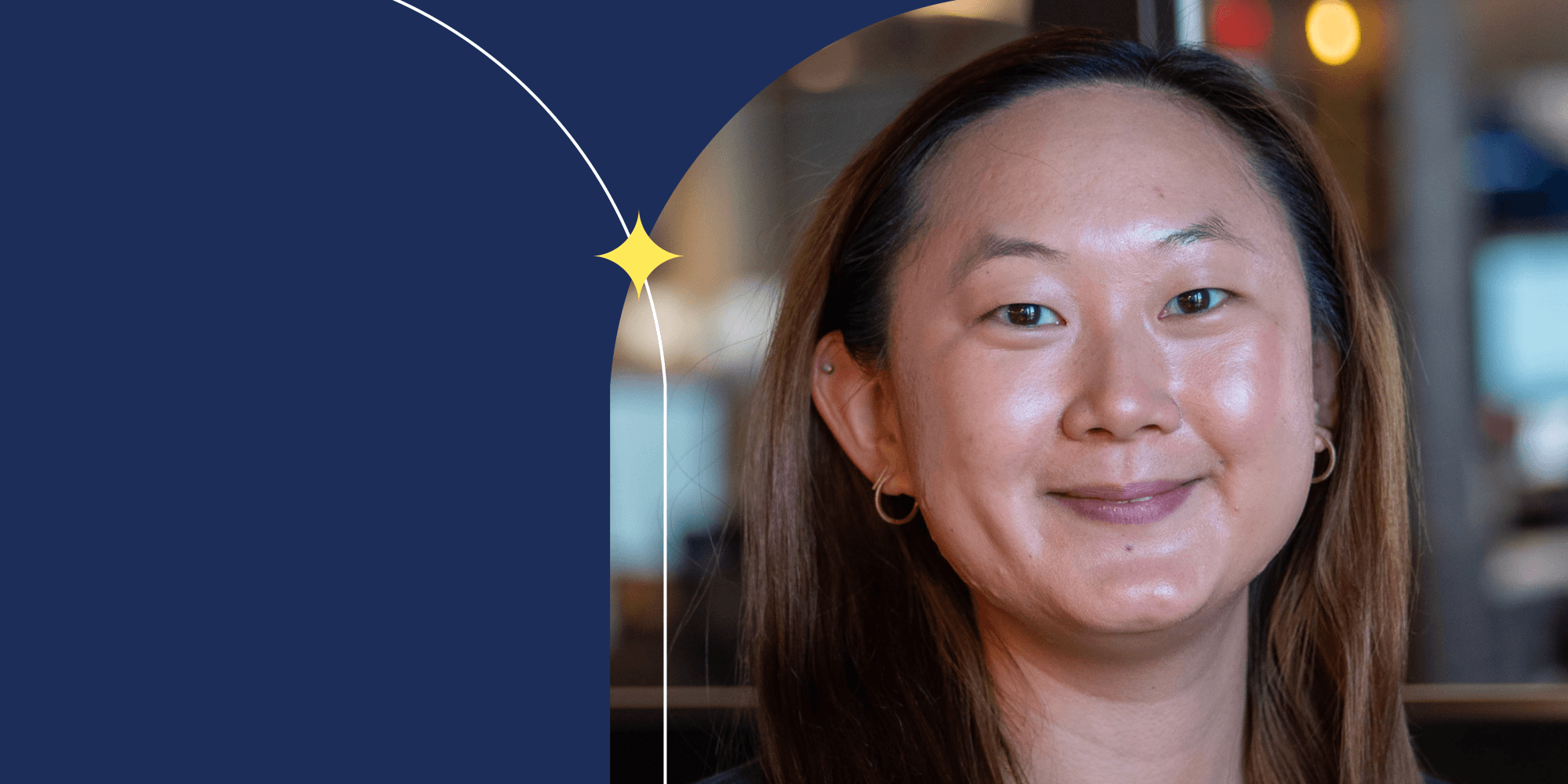 A person facing the camera and smiling. They have light brown hair and are wearing hoop earrings.