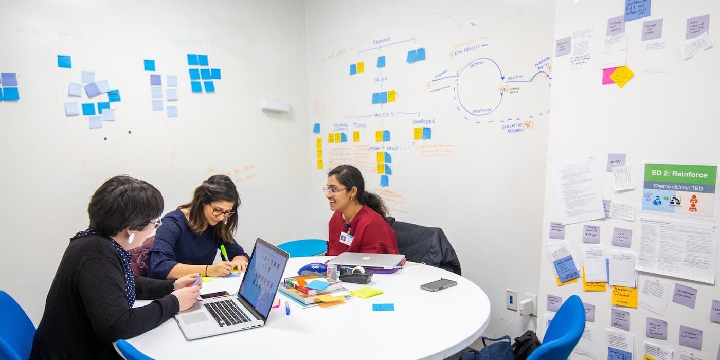Three MSK employees working together with sticky notes and a laptop.