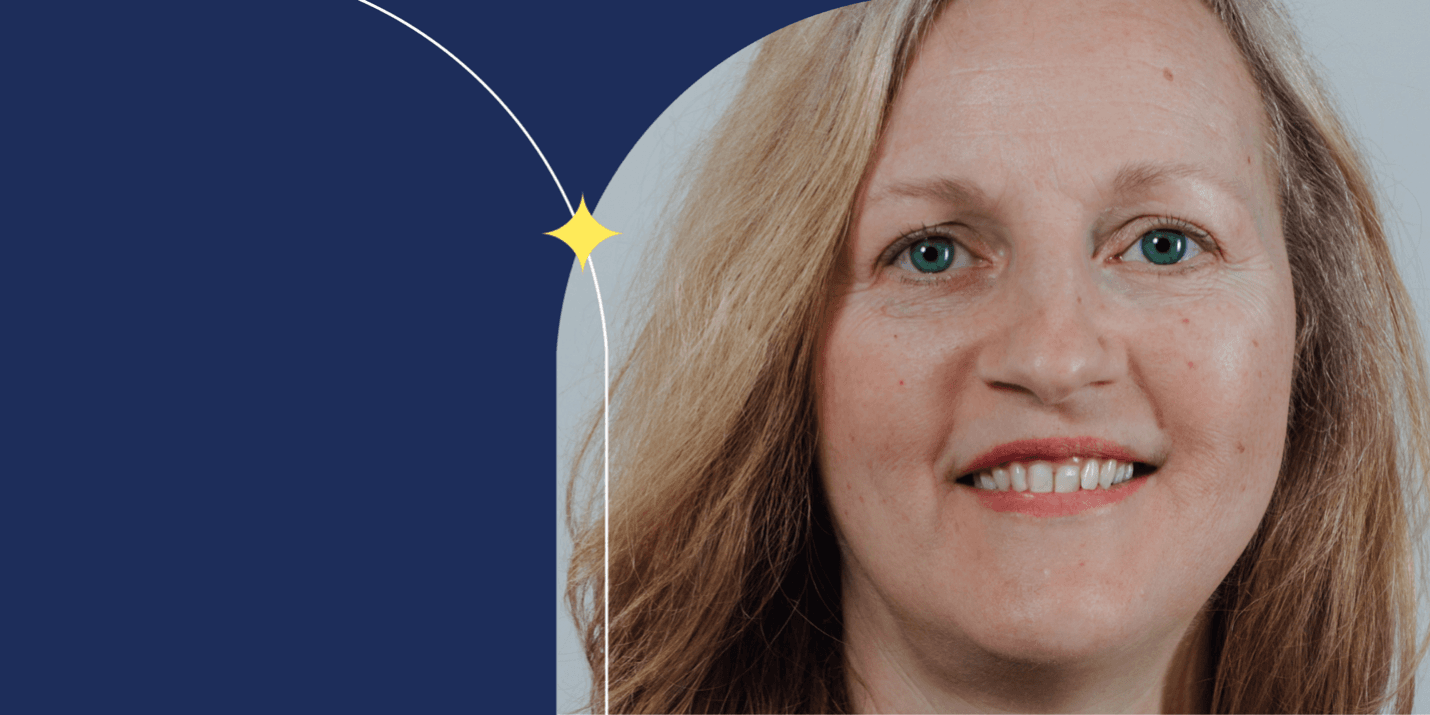 A person facing the camera and smiling. They have long blonde hair and blue eyes.