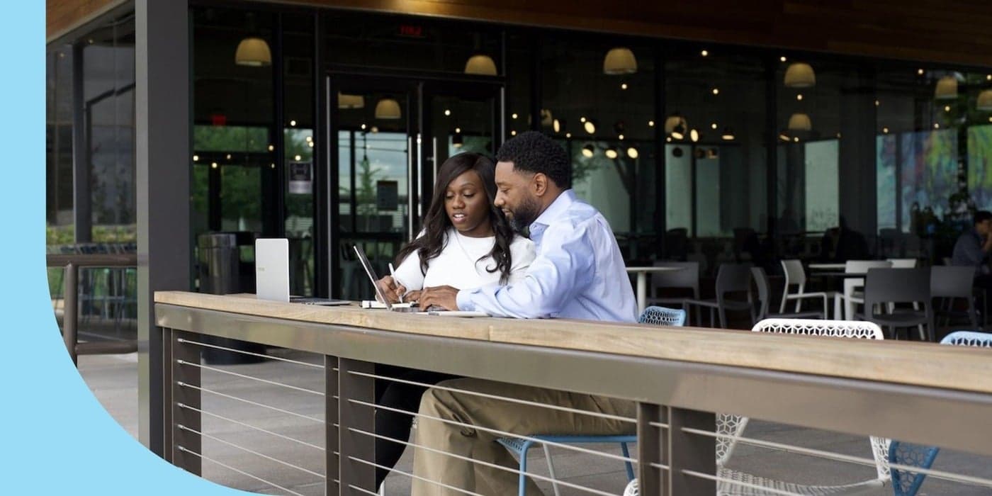 Two people working in an office’s outdoor patio space.