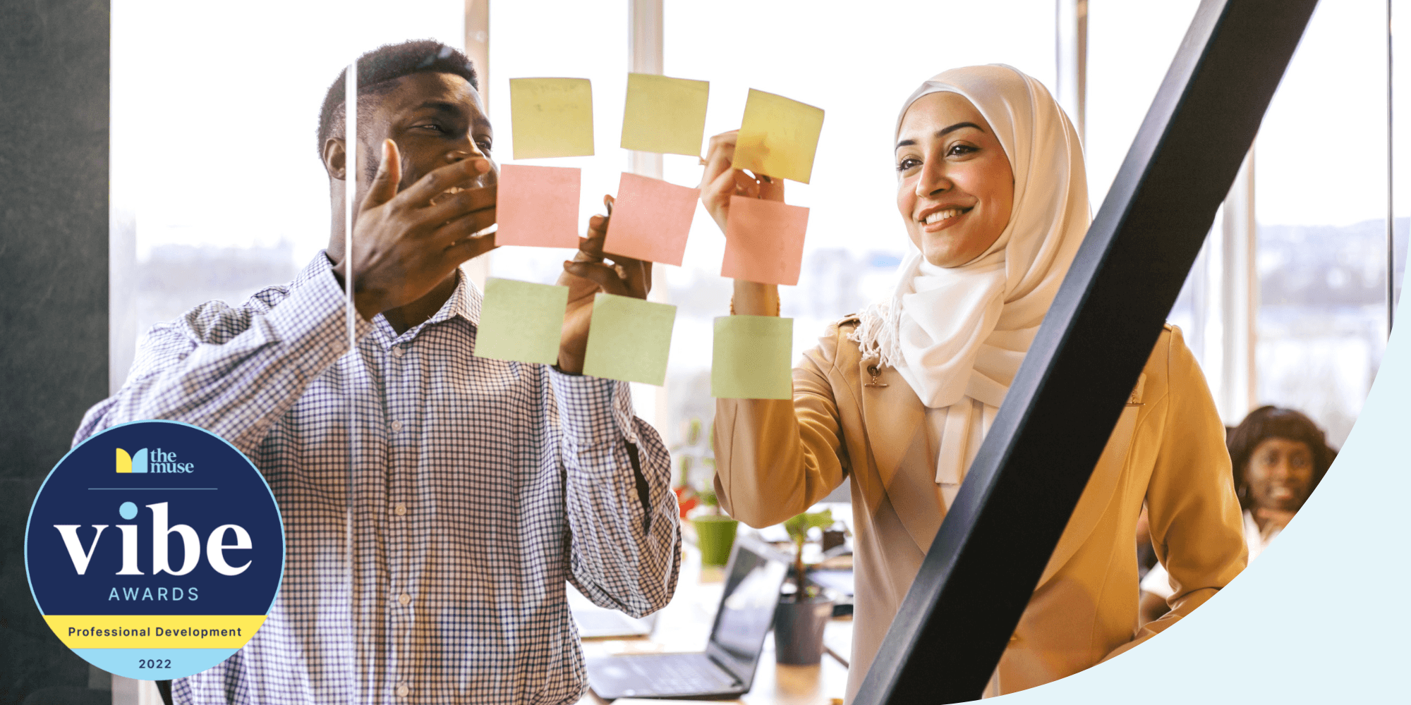 two coworkers looking at stick notes on the window of a conference room