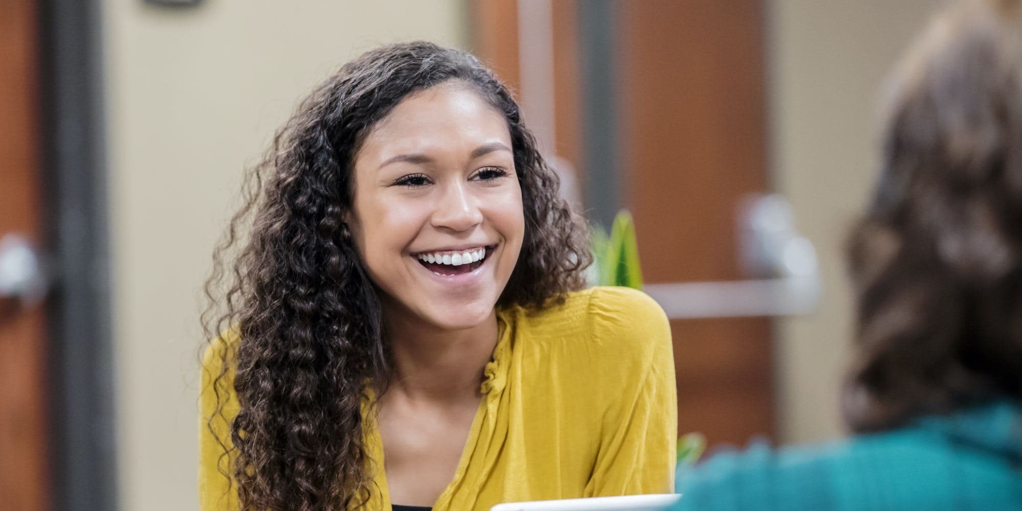 person smiling speaking to another person who's facing away from the camera