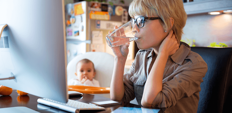 person working at home with baby sitting in chair nearby