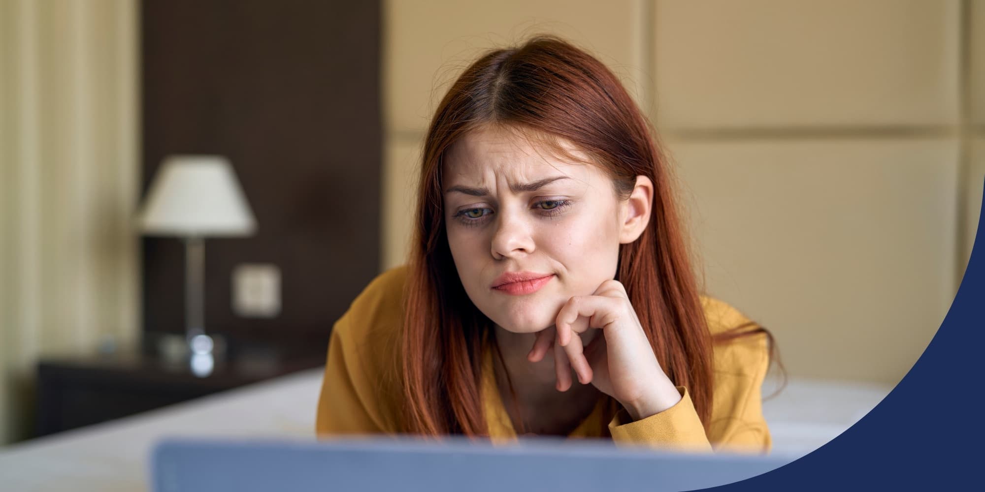 person working on laptop at home with their chin on one hand and their brow furrowed