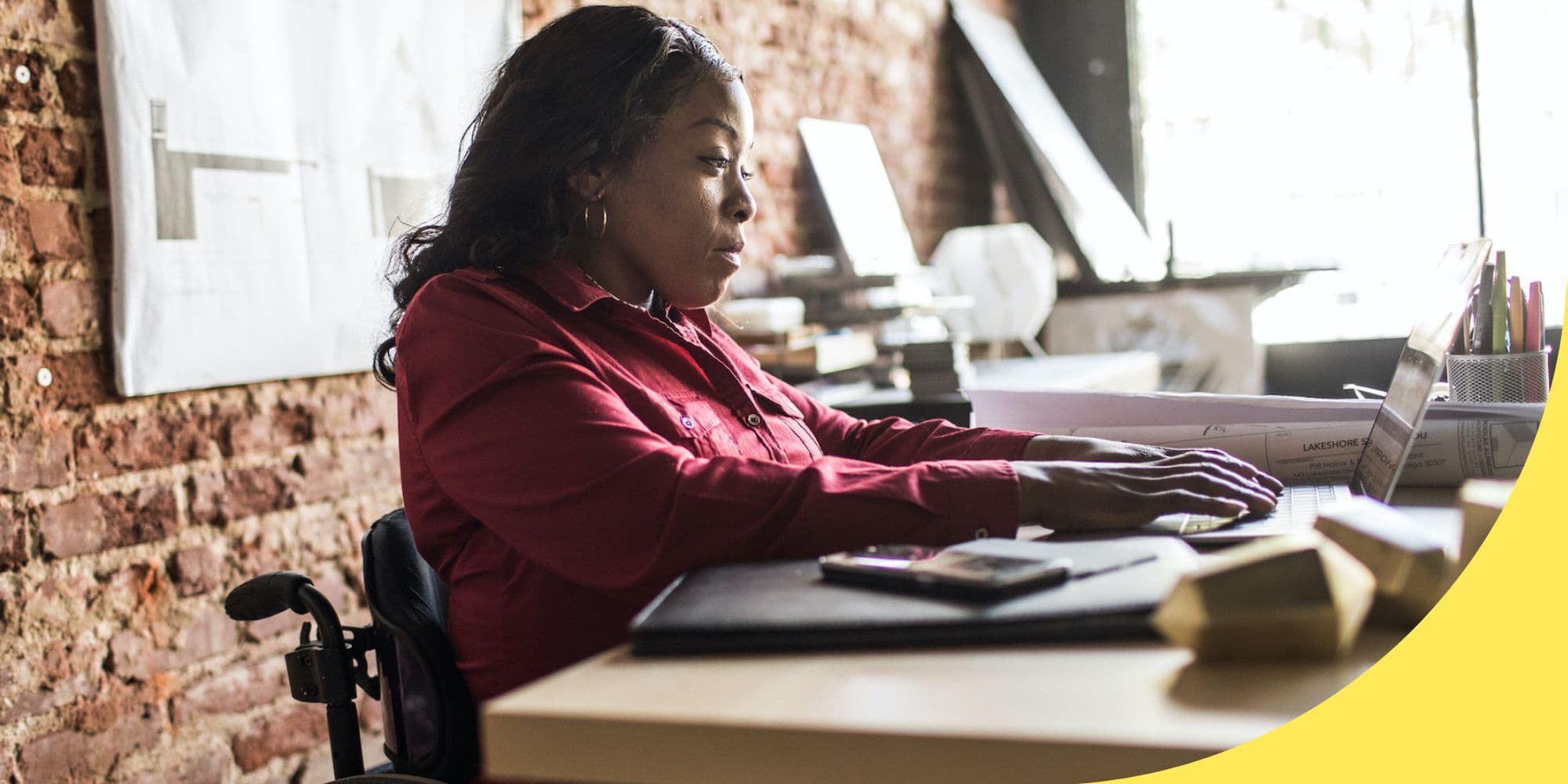 person at a desk in an office typing on a laptop
